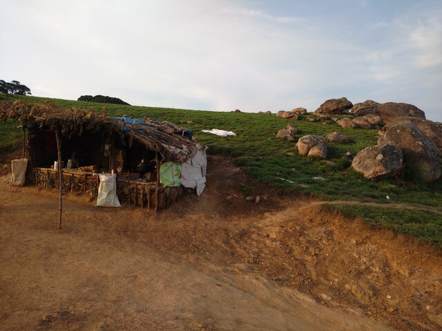 Picture showing a small shack selling water in the left, with a background of a grassy terrain and twilight sky.